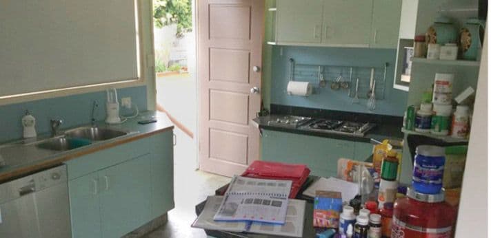 Kitchen before: blue splashback and cluttered benches