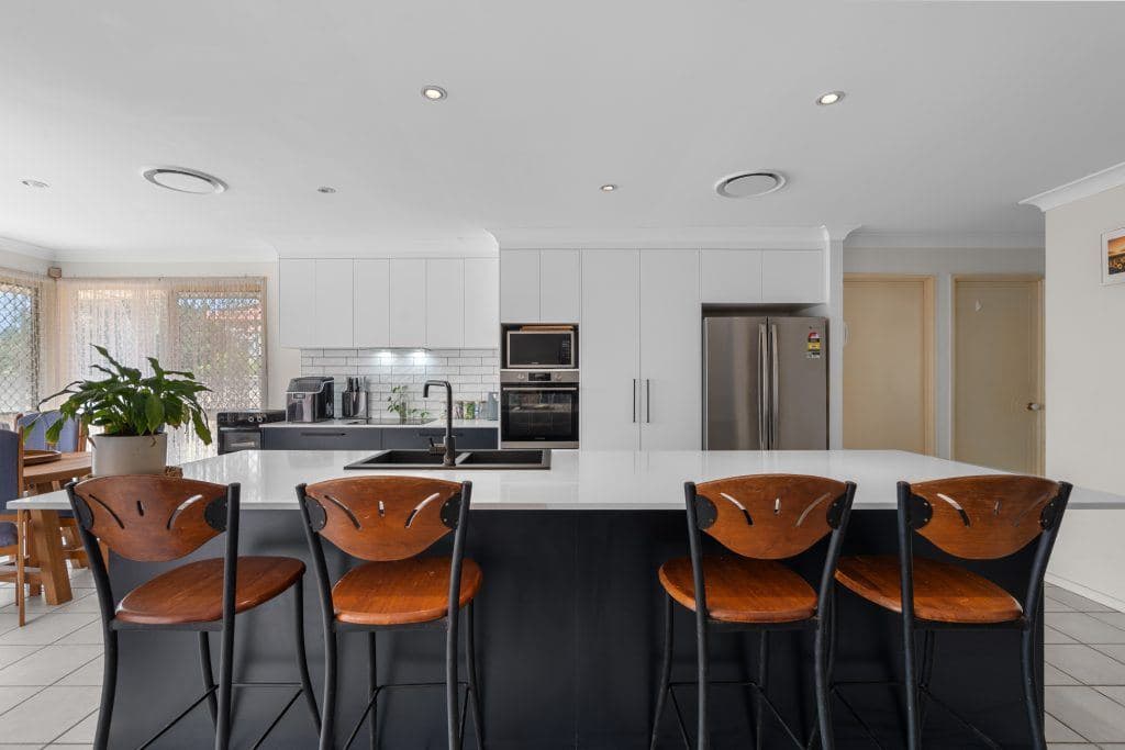 Kitchen island with stools and a white benchtop